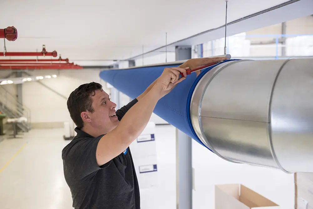 Monteur installeert textiele luchtverdeelslang met rails, kabels of katrols